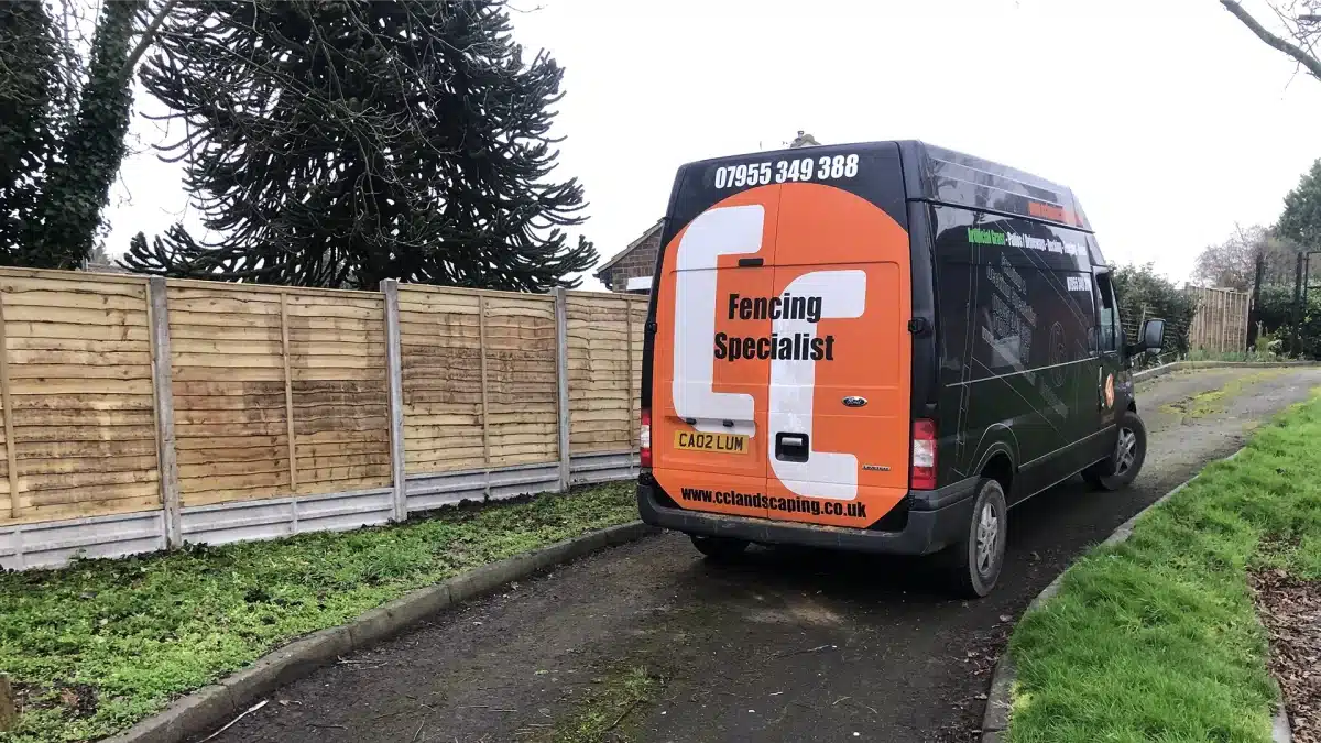 Fencing specialist van parked beside a newly installed wooden fence
