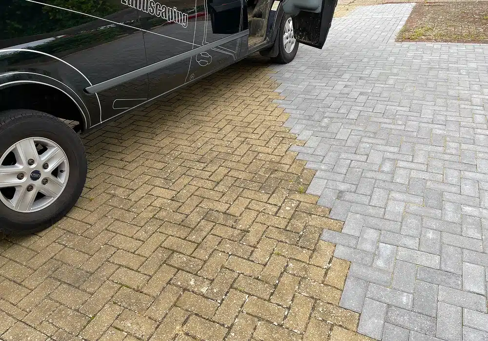 Black van parked on a driveway beside a newly laid grey block-paved section next to older tan paving