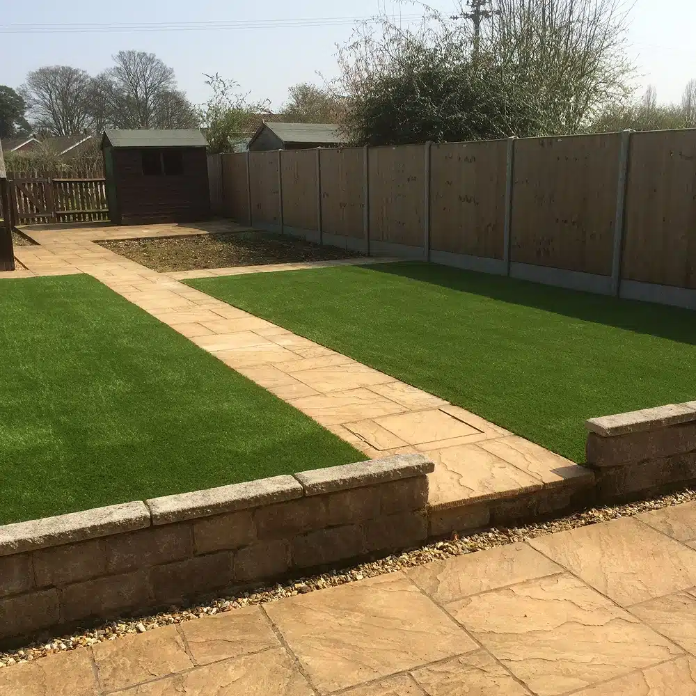 Back garden with paved paths, artificial grass and a wooden shed along the fence