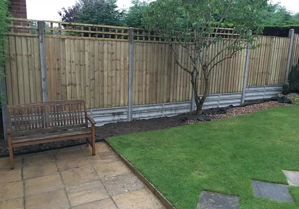 Garden with wooden bench, lawn, tree and fence