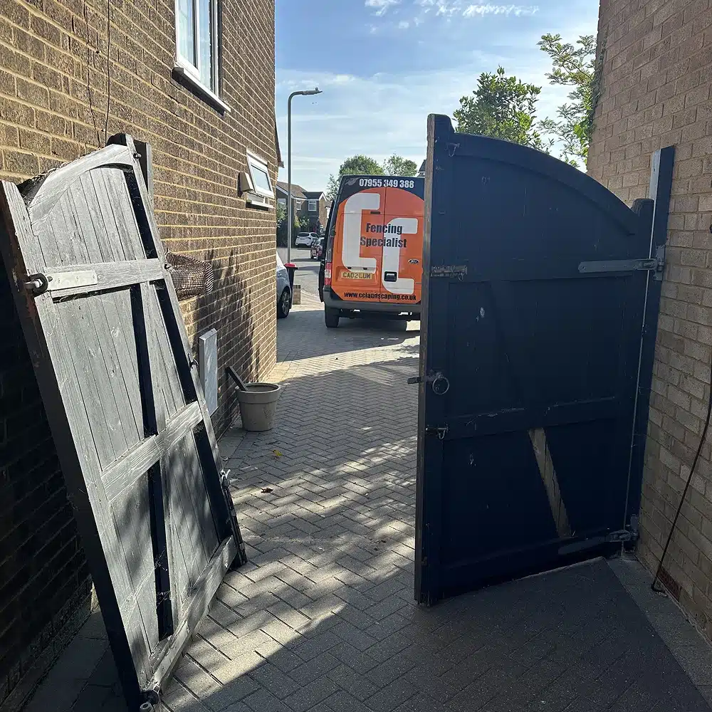Open wooden gates leading to a driveway, with a fencing specialist van parked outside