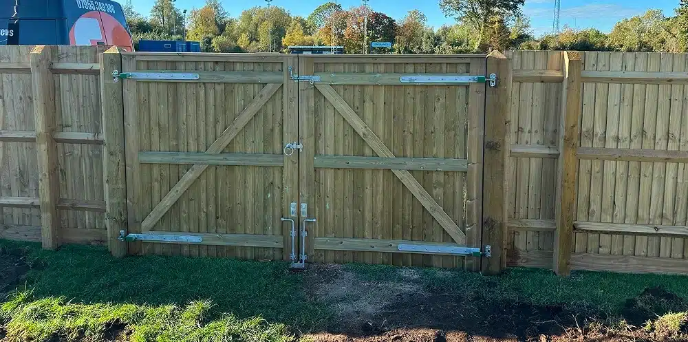 Wooden double driveway gate in a fence, with metal hinges and latches